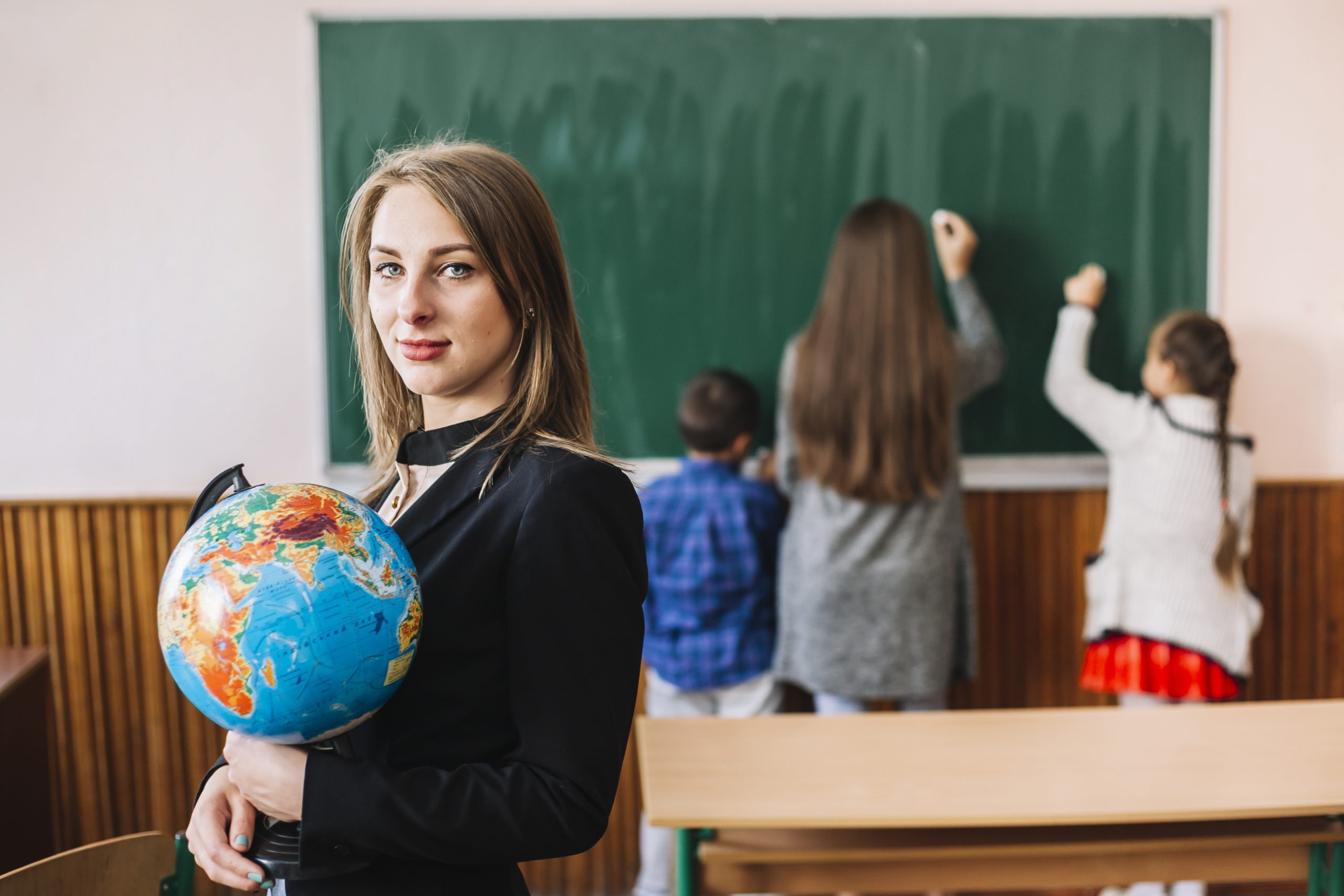 female-teacher-with-globe-classroom-background